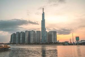 città di ho chi minh, vietnam, 11 febbraio 2022 vista del tramonto al punto di riferimento 81 - è un grattacielo super alto e un ponte saigon con edifici di sviluppo lungo il fiume saigon la luce si attenua foto