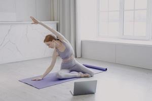 giovane donna che pratica yoga sul materassino. sport femminili e lezioni online a casa in quarantena. foto
