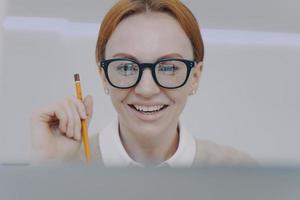 giovane donna che studia con la macchina fotografica. studente felice che tiene matita e prende appunti. insegnamento a distanza. foto