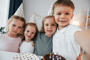 facendo selfie. festeggiare il compleanno. gruppo di bambini è insieme a casa durante il giorno foto