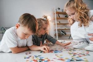 giocare a puzzle game. gruppo di bambini è insieme a casa durante il giorno foto