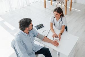 l'uomo maturo è con una dottoressa, in consultazione. l'operatore medico professionista in camice bianco è in ufficio foto