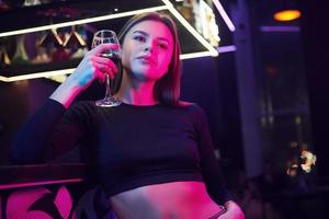 giovane donna in piedi nel night club con un drink in mano foto