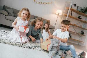 disimballaggio scatole regalo. festa di compleanno. gruppo di bambini è insieme a casa durante il giorno foto