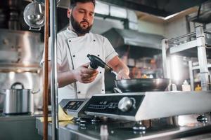 il cibo è sui pesi. fiamme nel piatto. chef professionista che prepara il cibo in cucina foto