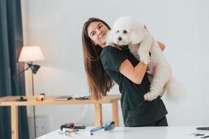 donna che tiene l'animale domestico. simpatico cagnolino è nello studio di toelettatura foto