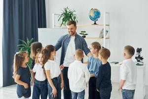 in piedi e dando il cinque. gruppo di bambini studenti in classe a scuola con l'insegnante foto