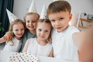 facendo selfie. festeggiare il compleanno. gruppo di bambini è insieme a casa durante il giorno foto