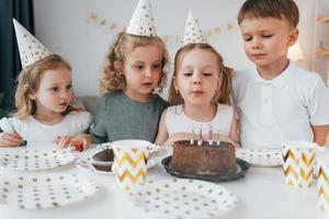 la torta dolce è sul tavolo. festeggiare il compleanno. gruppo di bambini è insieme a casa durante il giorno foto