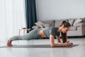 di giorno. facendo esercizi. la giovane donna con un tipo di corpo snello e in abiti da yoga è a casa foto