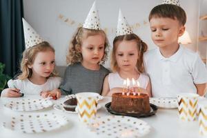 la torta dolce è sul tavolo. festeggiare il compleanno. gruppo di bambini è insieme a casa durante il giorno foto