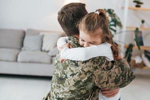 finalmente incontrarsi. il soldato in uniforme è a casa con la sua piccola figlia foto