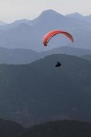 parapendio di fronte a un panorama di catena montuosa nelle alpi foto