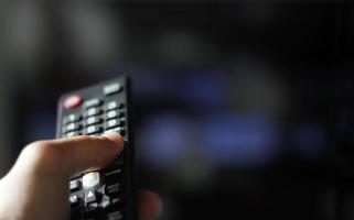 telecomando e schermo - abbuffarsi di guardare il programma televisivo preferito foto