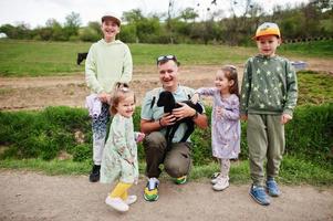 padre con quattro bambini in una fattoria ecologica animale tenere in mano l'agnello delle pecore. foto