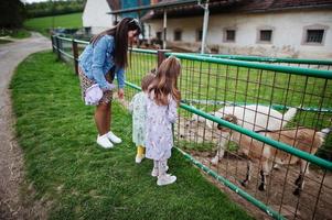 madre con bambini in una fattoria ecologica animale alimenta le capre. foto