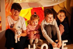 giocare ai bambini con il gattino in tenda di notte a casa. umore hygge. foto