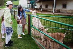 madre con bambini in una fattoria ecologica animale alimenta le capre. foto