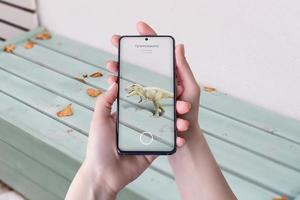 Proiezione di realtà aumentata di dinosauri 3d sul tavolo con smartphone. il concetto di utilizzare la tecnologia nell'istruzione e nell'intrattenimento foto