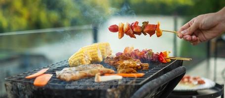 deliziosa carne alla griglia con fumo, barbecue con verdure all'aperto. concetto di barbecue, festa, stile di vita e picnic foto