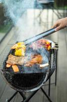 deliziosa carne alla griglia con fumo, barbecue con verdure all'aperto. concetto di barbecue, festa, stile di vita e picnic foto