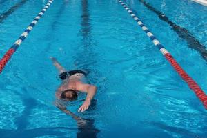 uomo di mezza età che nuota nella piscina all'aperto. foto