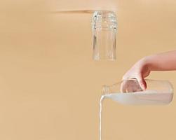latte che fuoriesce da una bottiglia di vetro. bicchiere capovolto. concetto creativo di prodotti lattiero-caseari. copia spazio foto