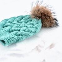 cappello turchese lavorato a maglia o berretto con pon pon su una neve. concetto di abbigliamento invernale. bambini vestiti caldi e accessori. lavorare a maglia come hobby foto