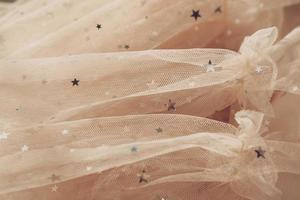 tessuto festivo in tulle con stelle. trama di tessuto a rete beige foto