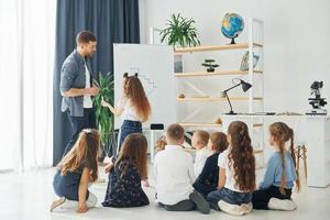 scrivendo alla lavagna. gruppo di bambini studenti in classe a scuola con l'insegnante foto