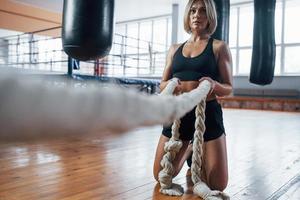 routine fisica. la donna bionda di sport ha esercizio con le corde in palestra. femmina forte foto