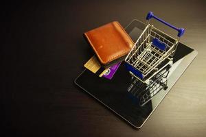 smart phone con carrello su legno, significa fare shopping online foto