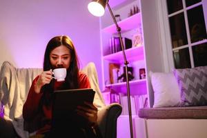 giovane donna che utilizza una tavoletta digitale a casa di notte. concetto di tecnologia, internet e persone foto