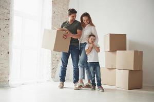 questa casa è nostra adesso. umore giocoso del bambino. la famiglia viene trasferita in una nuova casa. disimballo scatole per trasloco foto