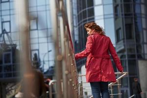 non c'è bisogno di affrettarsi oggi, è giorno libero. una bella donna adulta con un caldo cappotto rosso ha camminato in città durante i fine settimana foto