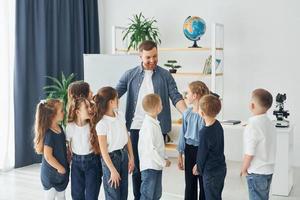 in piedi e dando il cinque. gruppo di bambini studenti in classe a scuola con l'insegnante foto