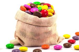 caramelle al cioccolato colorate in mini borsa a sacco su sfondo bianco foto