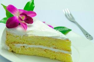 torta al cocco decorata da orchidea viola e foglia verde su piatto bianco foto