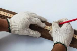 le mani del falegname usando un righello pieghevole in legno per misurare il suo lavoro di taglio del legno foto