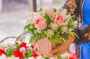 signora tiene in mano un bouquet di rose rosa in un secchio foto