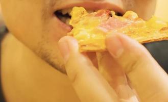 il primo piano di un uomo sta mangiando la pizza foto