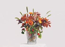 fiori e foglie autunnali in un vaso di cristallo foto
