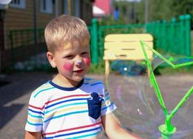 ragazzino carino con pittura del viso. ragazzo caucasico che soffia bolle di sapone foto