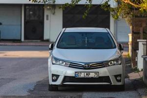 manavgat turchia 05 marzo 2022 la toyota corolla bianca è parcheggiata per strada in una calda giornata sullo sfondo di un edificio, alberi foto