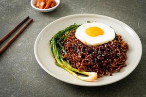 noodles istantanei con salsa nera piccante coreana essiccata con uovo fritto e kimchi foto