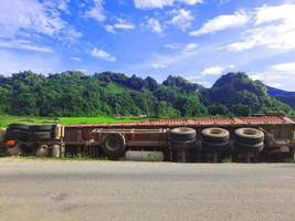 il camion degli incidenti cade dalla strada al campo di riso verde con la montagna e il cielo blu. foto