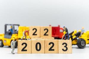 la squadra di lavoratori in miniatura crea il numero 2023 su un blocco di legno foto