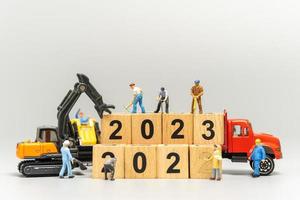 la squadra di lavoratori in miniatura crea il numero 2023 su un blocco di legno foto