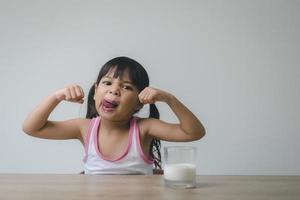 la bambina asiatica sta bevendo il latte da un bicchiere che era molto felice. foto