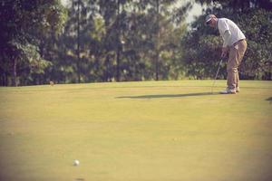 giocatore di golf al putting green che colpisce la palla in un colore hole.vintage foto